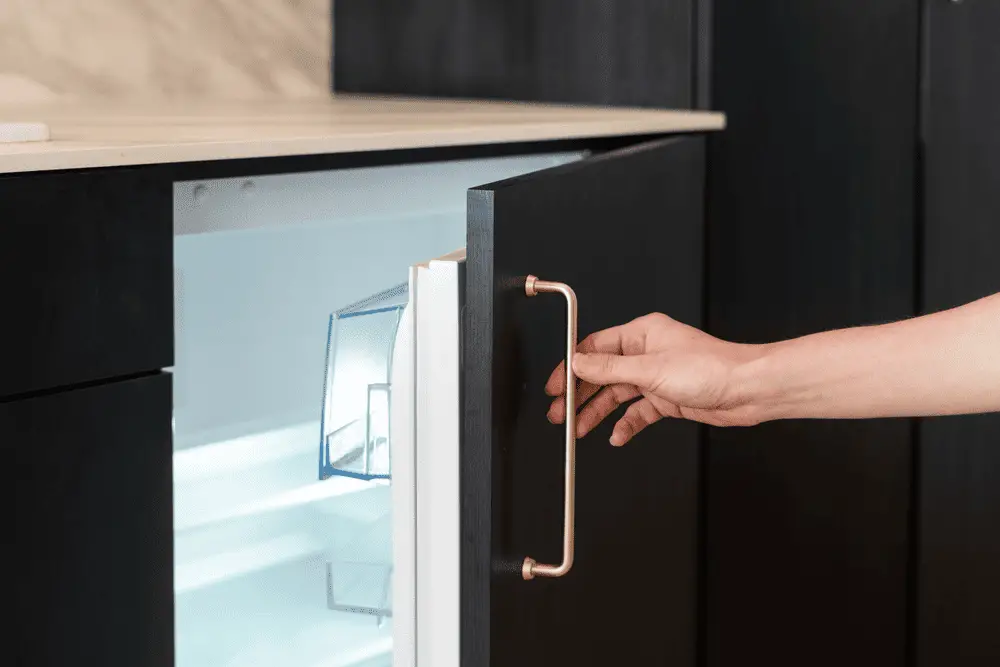 woman's hand opening a compact fridge